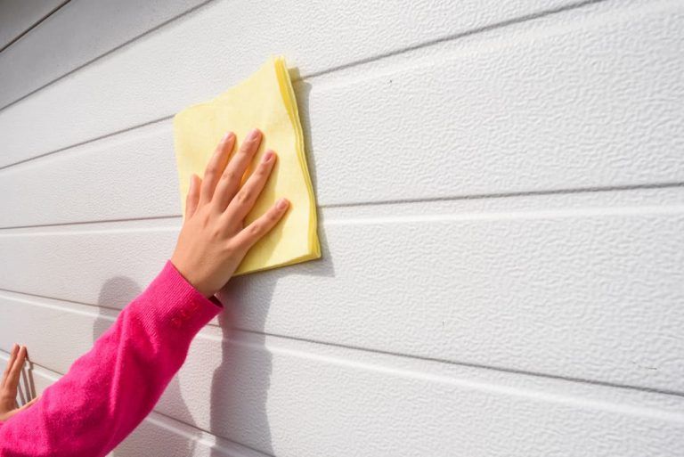 Person cleaning roller shutter garage doors with a soft cloth